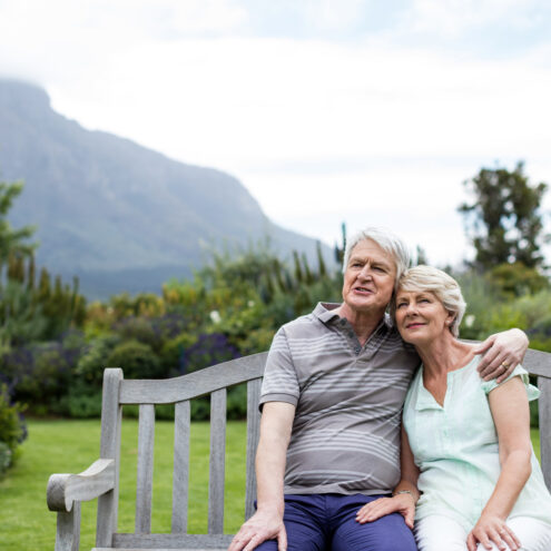 Senior couple sitting on a bench in lawn